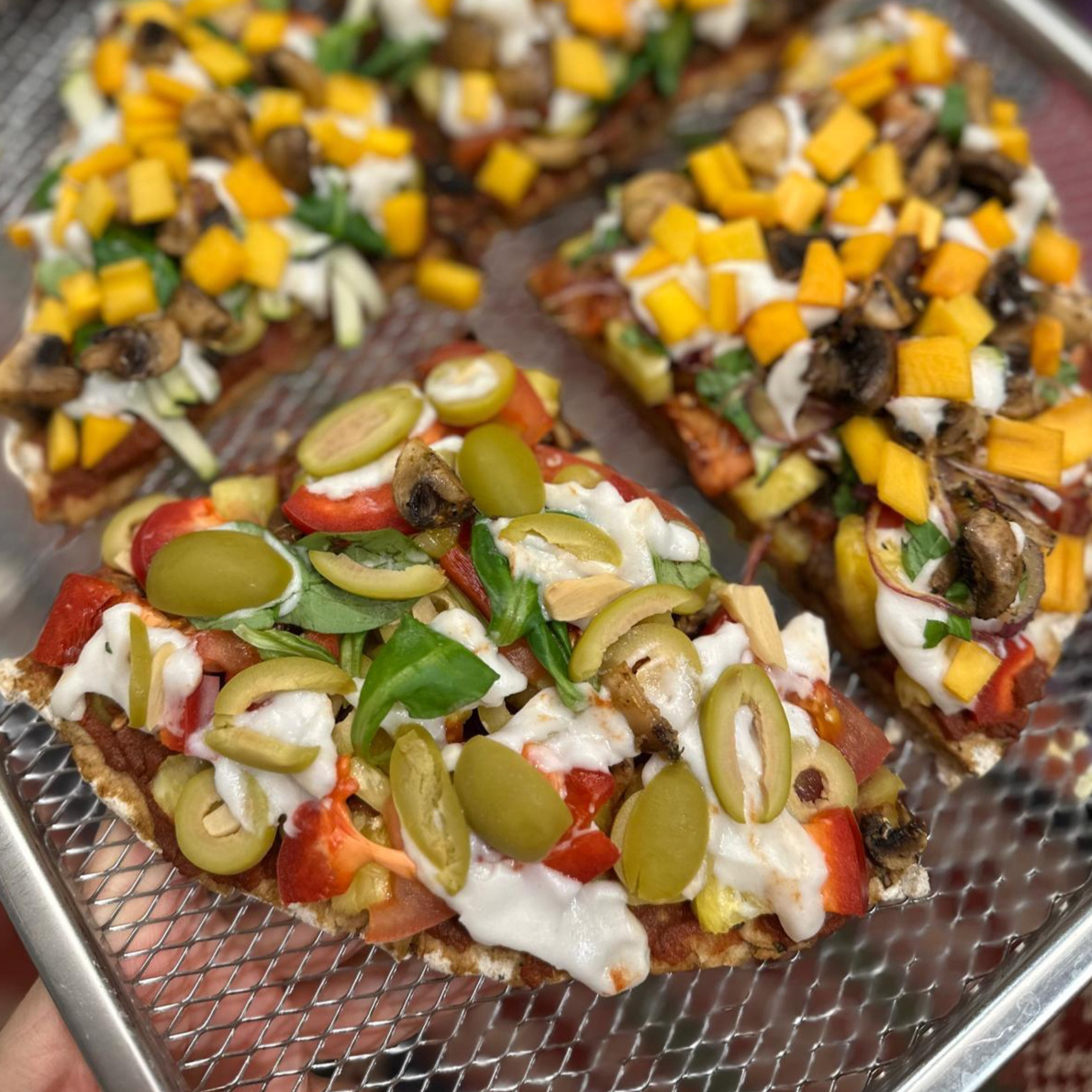 Surowa pizza wegańska z oliwkami i warzywami, przygotowana bez obróbki termicznej.